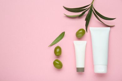 Photo of Tubes of natural cream with olive essential oil on pink background, flat lay. Space for text