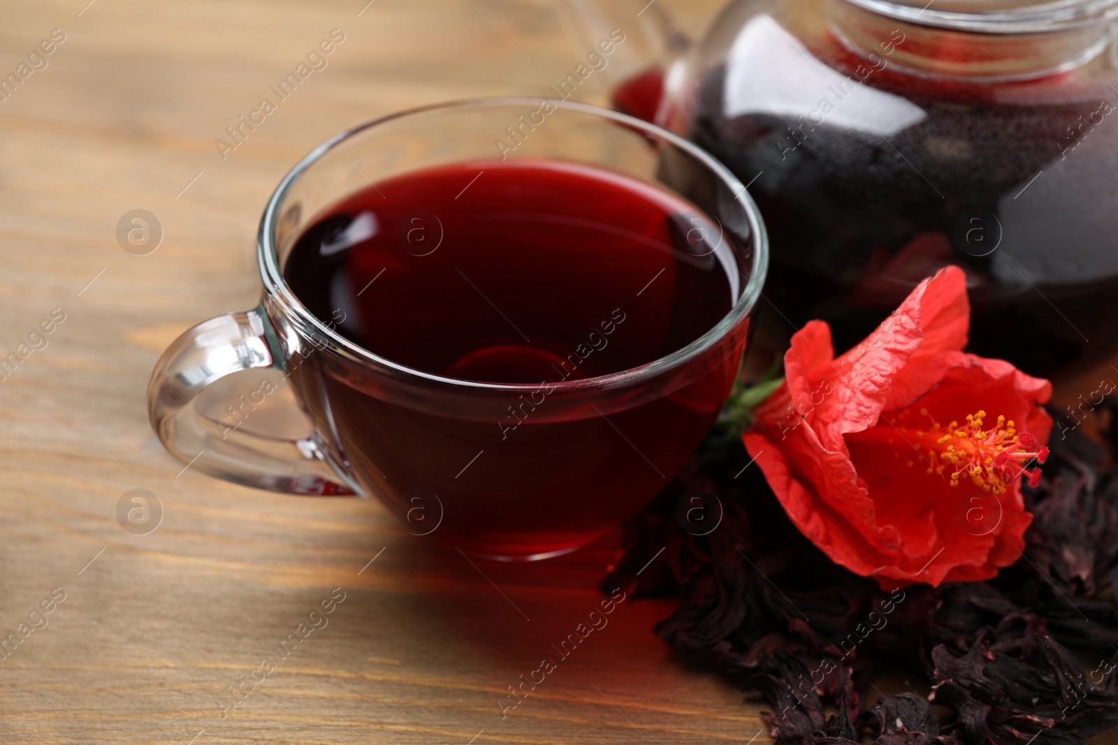 Photo of Delicious hibiscus tea and flower on wooden table, closeup