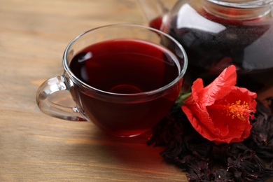 Photo of Delicious hibiscus tea and flower on wooden table, closeup