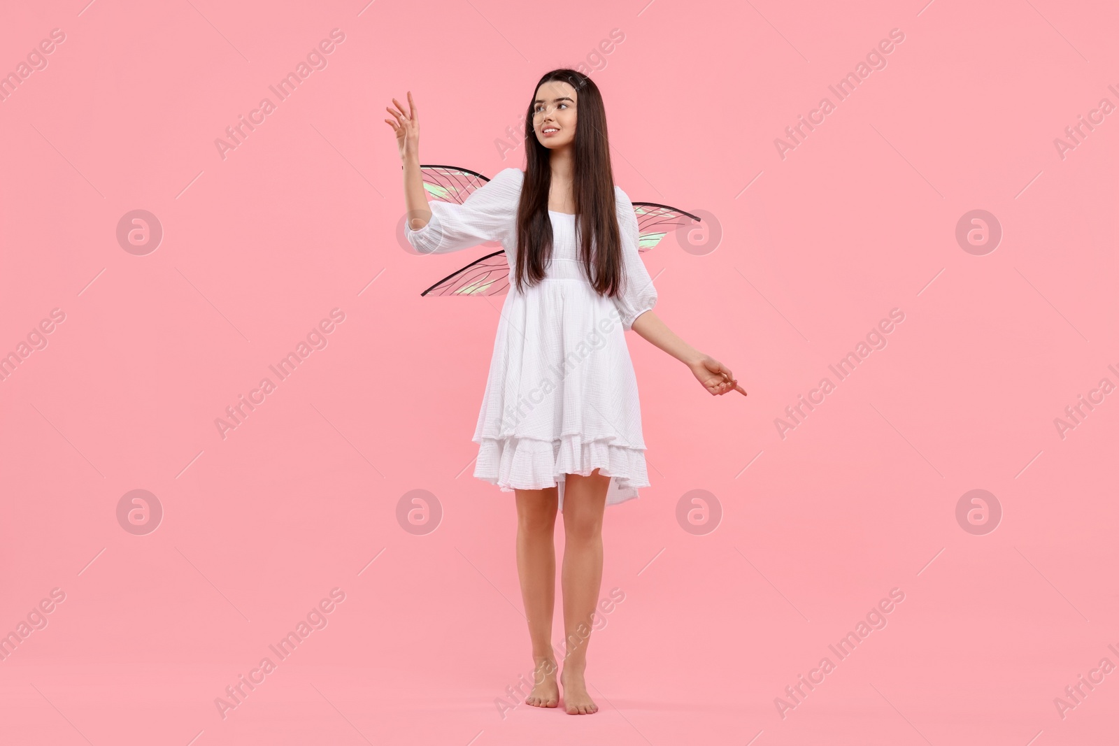 Photo of Beautiful girl in fairy costume with wings on pink background