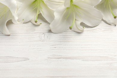 Photo of Beautiful lily flowers on white wooden table, flat lay. Space for text