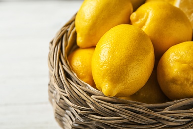 Basket with ripe lemons on wooden background, closeup