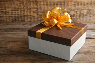 Photo of Beautiful gift box with bow on wooden table