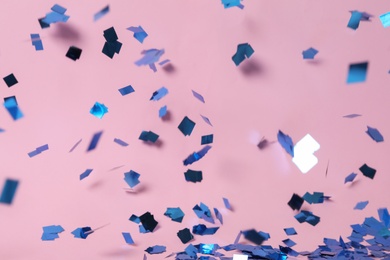 Photo of Shiny blue confetti falling down on pink background