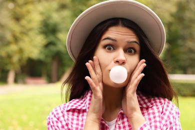 Photo of Beautiful young woman blowing chewing gum outdoors
