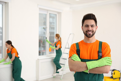 Photo of Professional young janitor in uniform indoors. Cleaning service