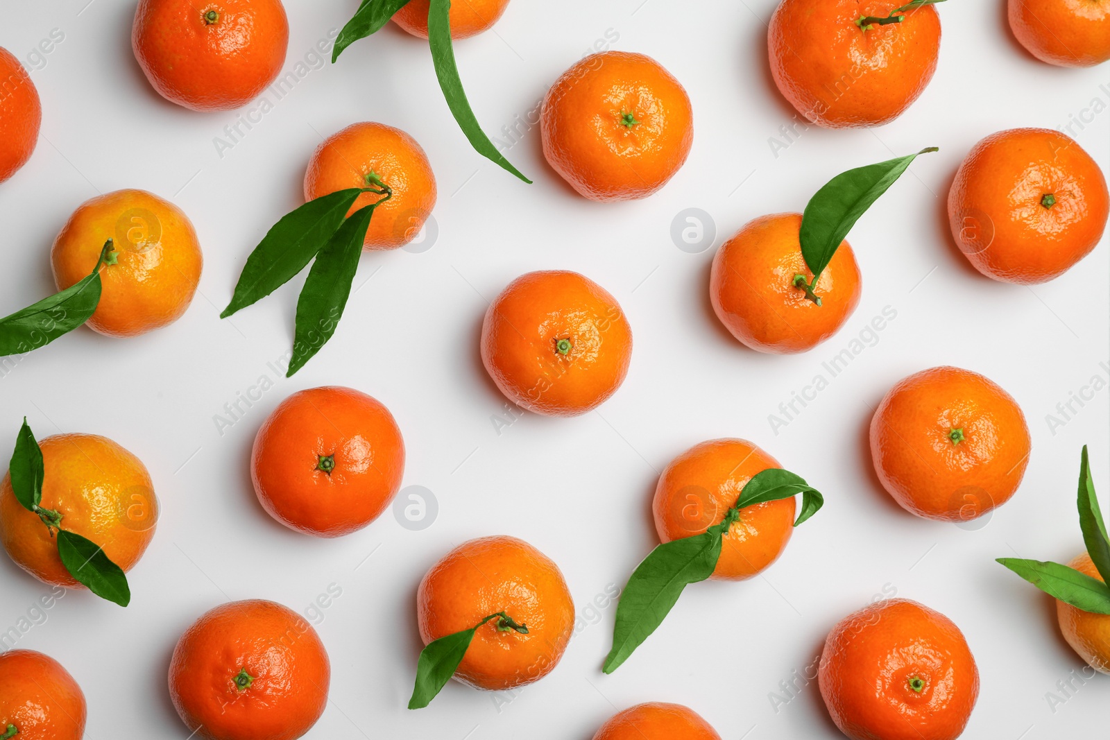 Photo of Delicious tangerines and green leaves on white background, flat lay