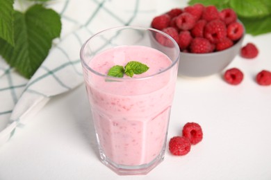 Glass of tasty raspberry smoothie on white table