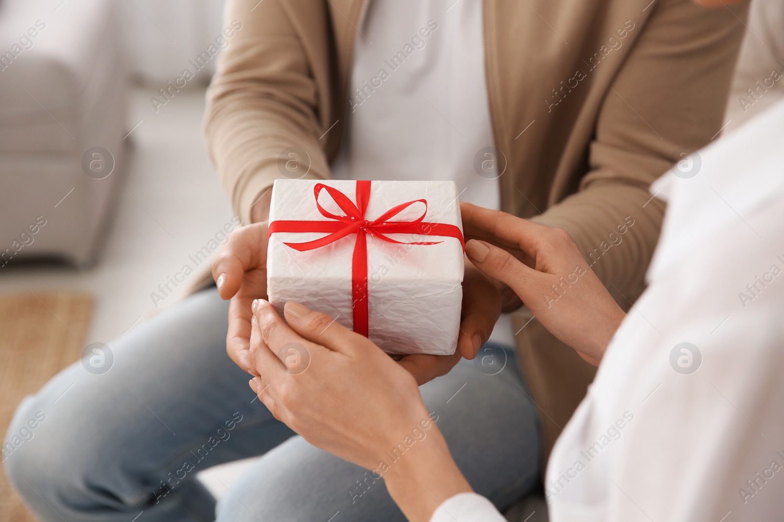 Photo of Man presenting gift to his beloved woman at home, closeup. Valentine's day celebration