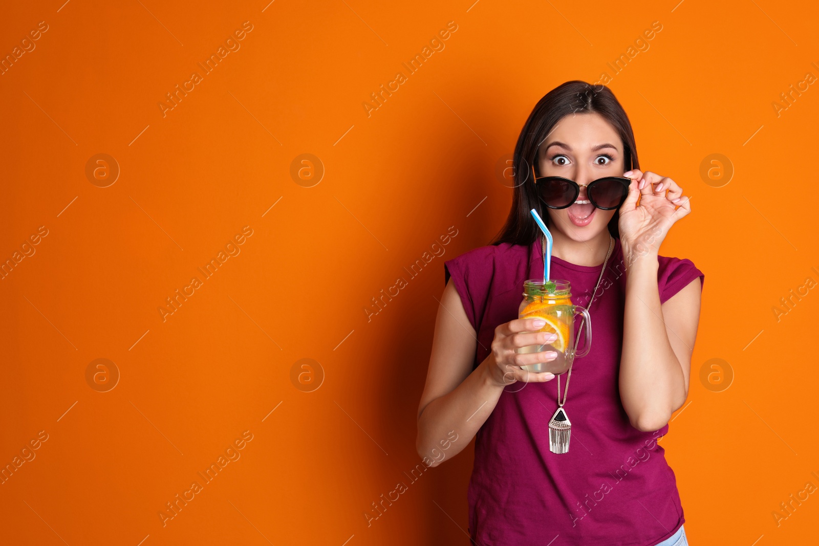 Photo of Young woman with mason jar of tasty lemonade on color background. Natural detox drink