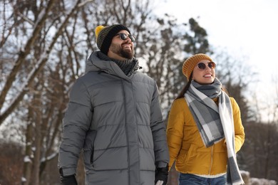 Beautiful happy couple walking in snowy park on winter day