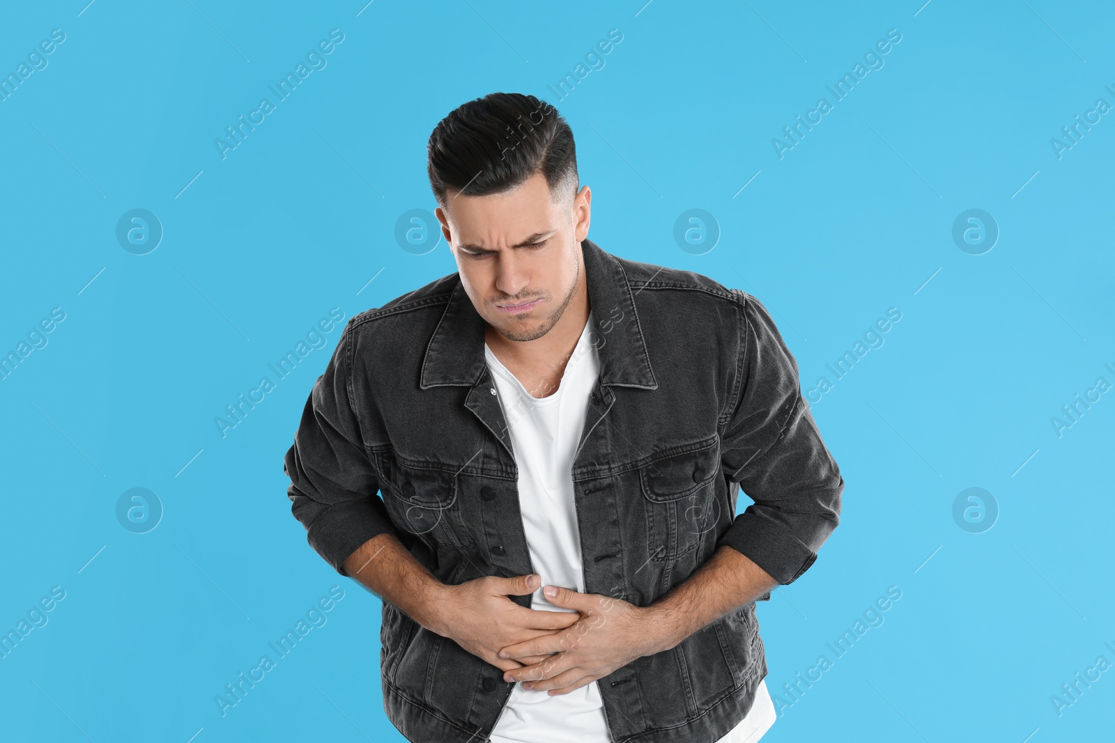 Photo of Man suffering from stomach ache and nausea on light blue background. Food poisoning