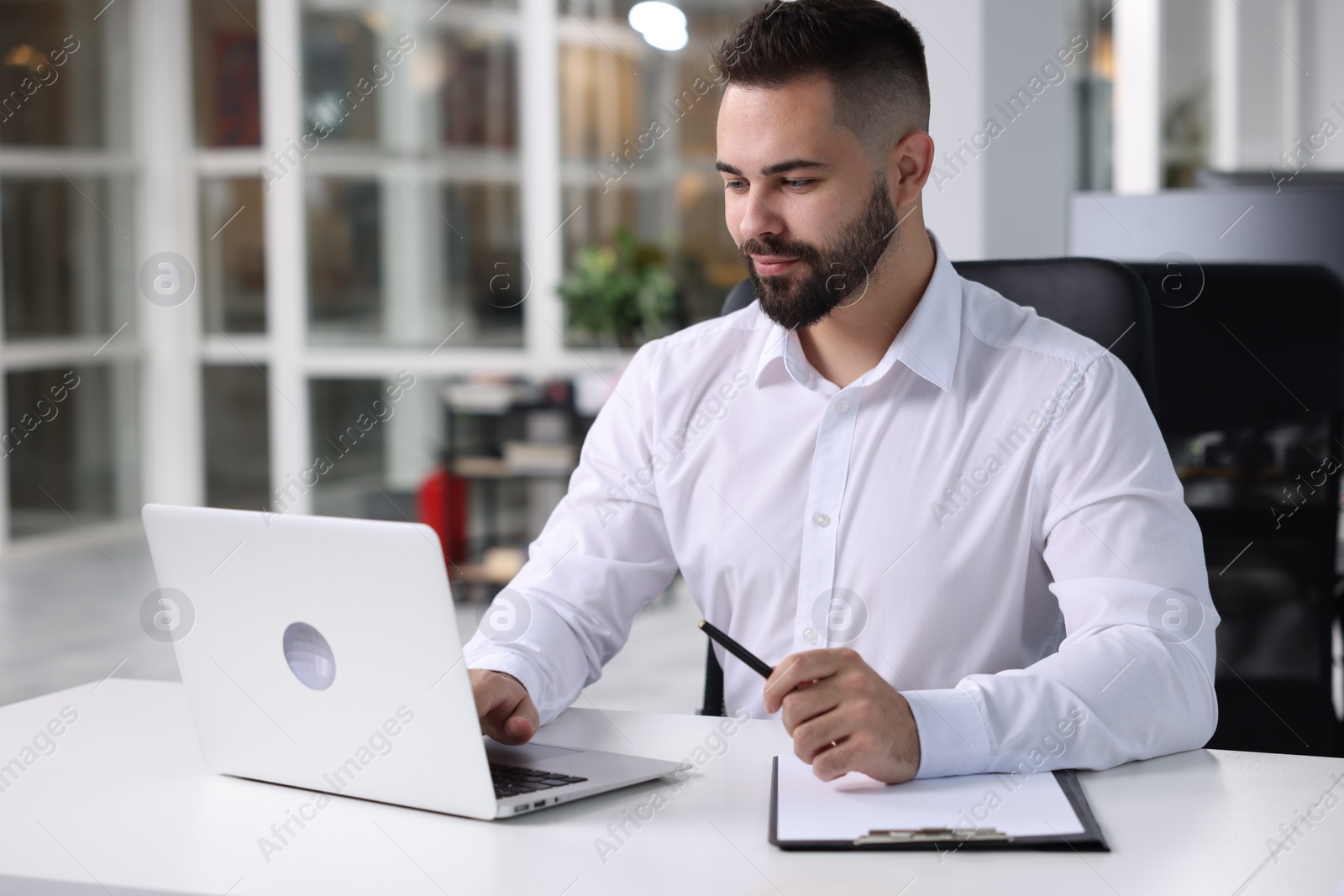 Photo of Handsome man working at table in office. Lawyer, businessman, accountant or manager