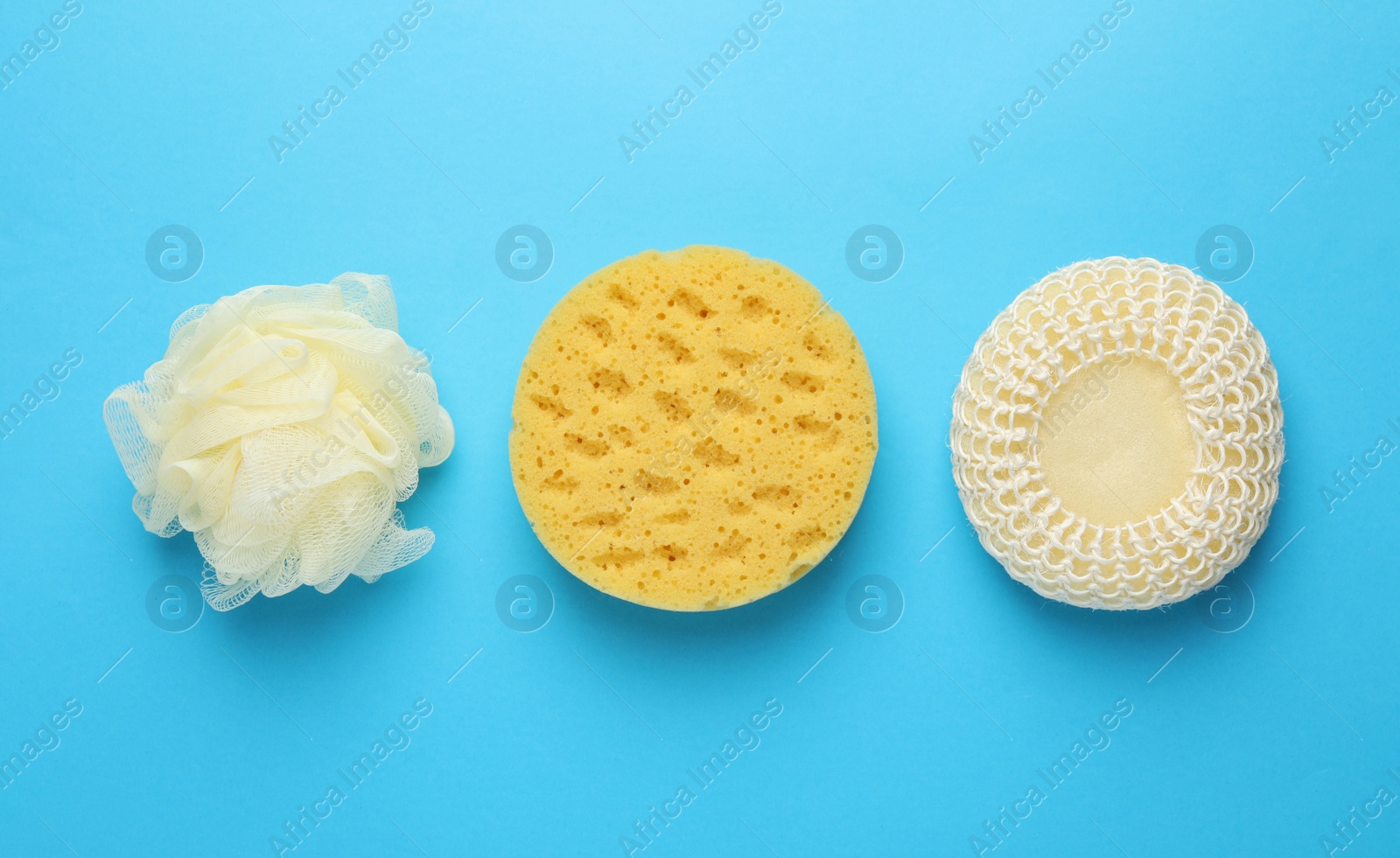 Photo of Different sponges on light blue background, flat lay