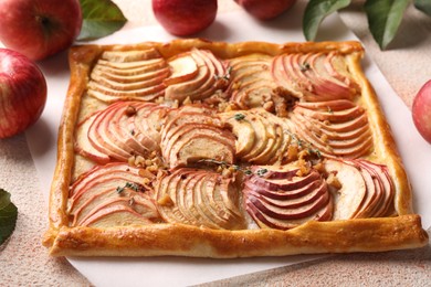 Photo of Tasty apple pie with nuts and fresh fruits on beige textured table, closeup