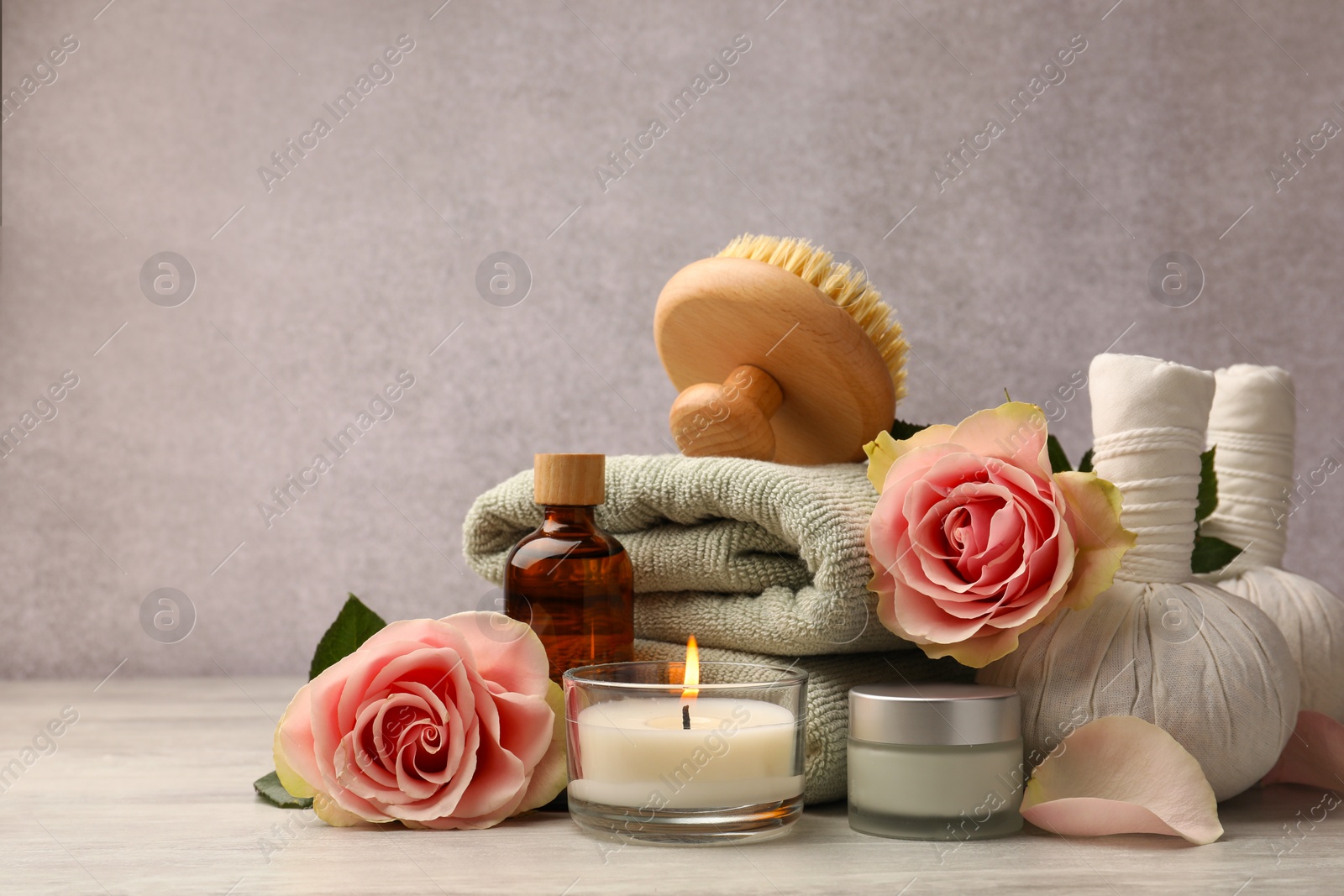 Photo of Composition with spa products, roses and candle on grey wooden table. Space for text