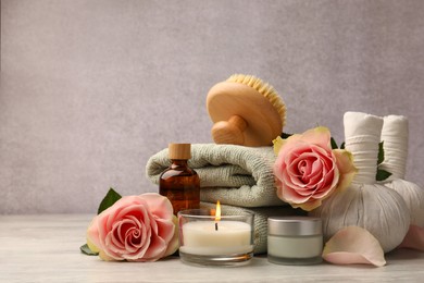 Photo of Composition with spa products, roses and candle on grey wooden table. Space for text