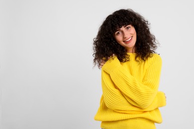 Happy young woman in stylish yellow sweater on white background, space for text