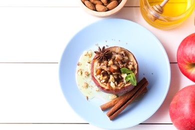 Photo of Tasty baked apple with nuts, honey, spices and mint on white wooden table, flat lay. Space for text