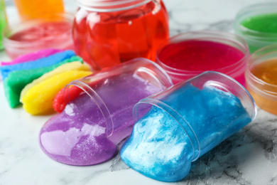 Photo of Different bright slimes on white marble background, closeup