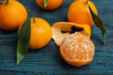 Photo of Fresh ripe tangerines with green leaves on table