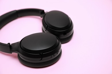 Photo of Modern wireless headphones on pink background, closeup. Space for text