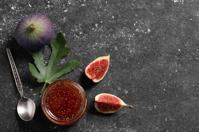 Photo of Jar with tasty sweet jam, fresh figs and spoon on black textured table, flat lay. Space for text