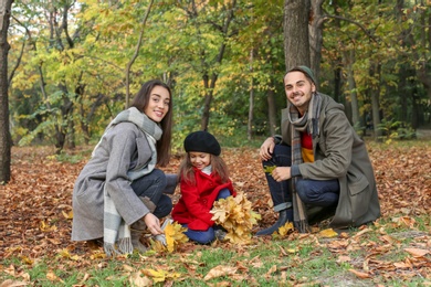 Photo of Happy family with child spending time together in park. Autumn walk
