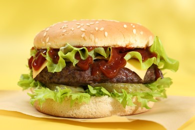 Photo of Burger with delicious patty on yellow background, closeup