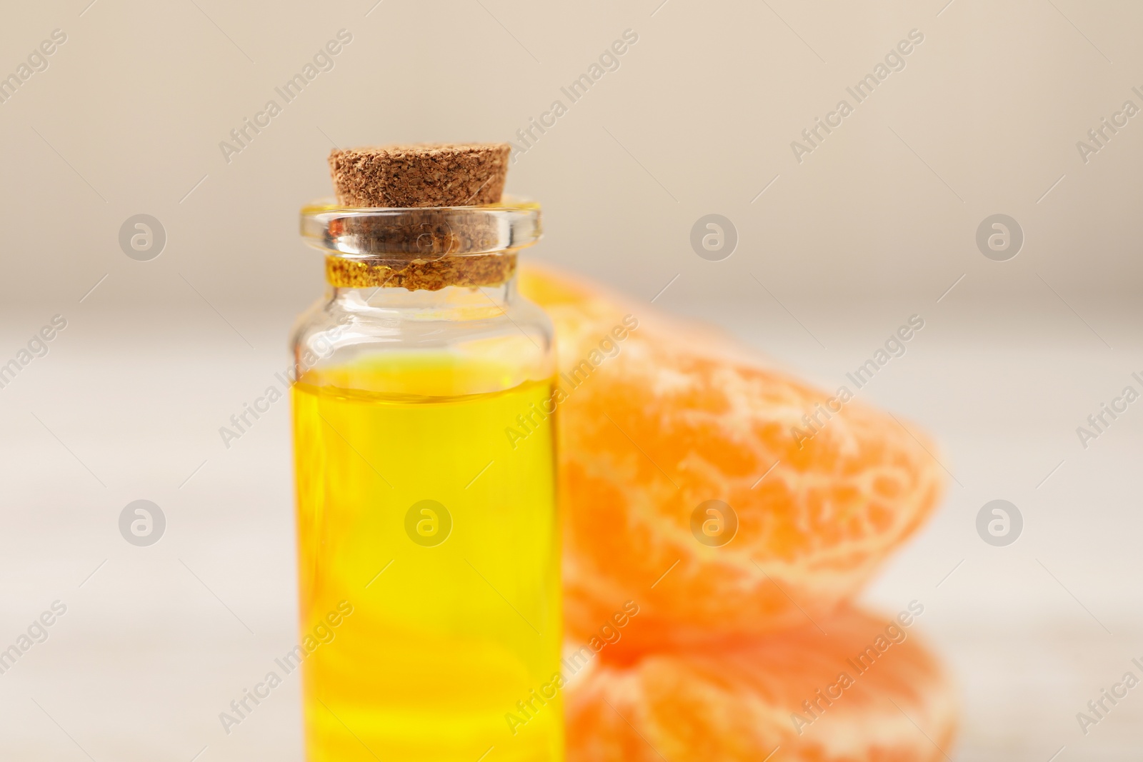 Photo of Bottle of tangerine essential oil and fresh fruit on table, closeup