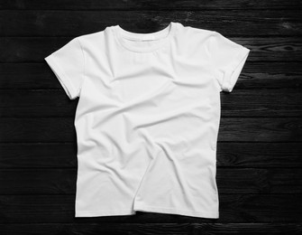 Photo of Stylish white t-shirt on black wooden background, top view