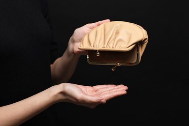 Woman with empty wallet on black background, closeup