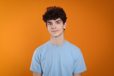 Portrait of cute teenage boy on orange background