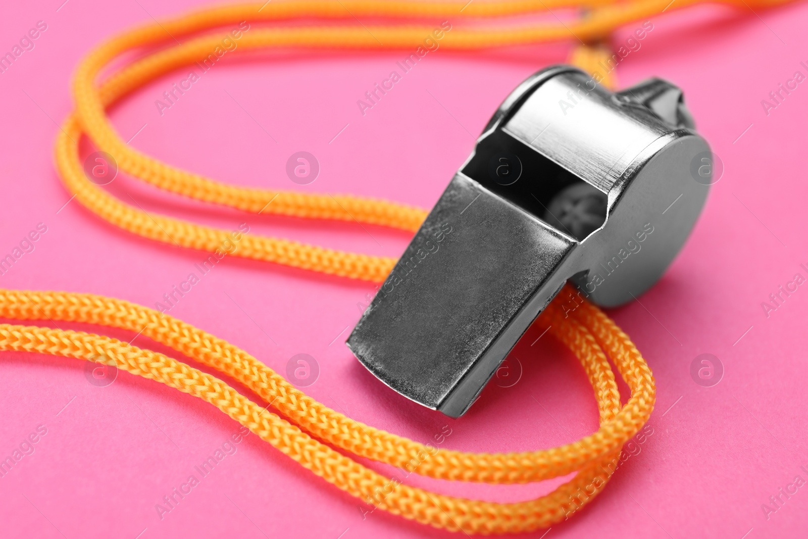 Photo of One metal whistle with cord on pink background, closeup