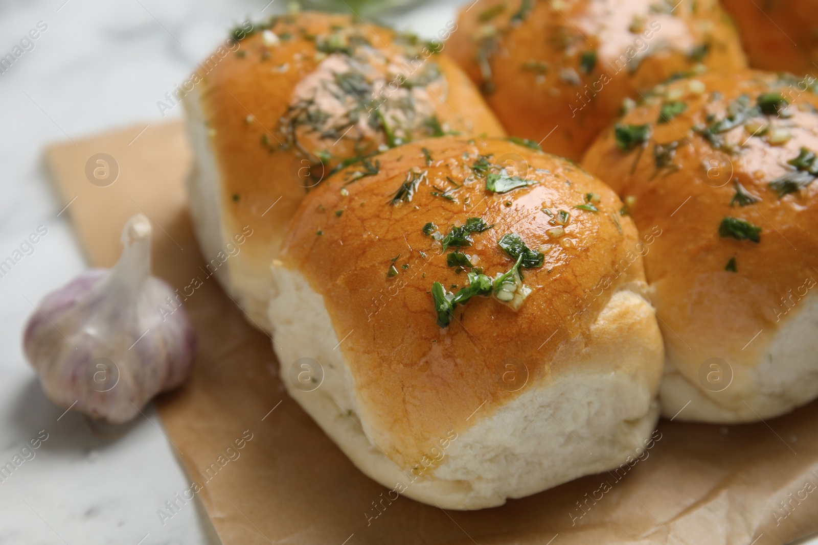 Photo of Traditional pampushka buns with garlic and herbs on white table, closeup