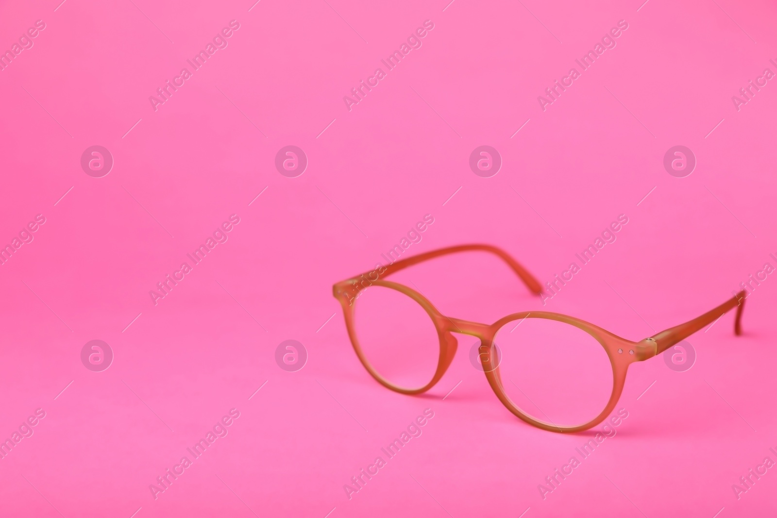 Photo of Glasses with corrective lenses on bright pink background. Space for text