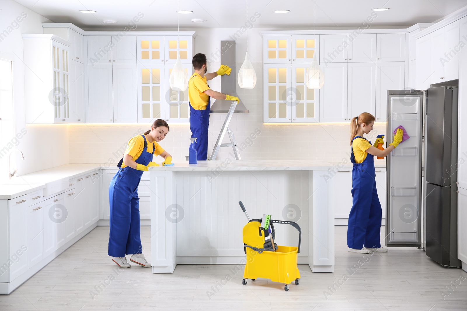 Photo of Team of professional janitors cleaning modern kitchen