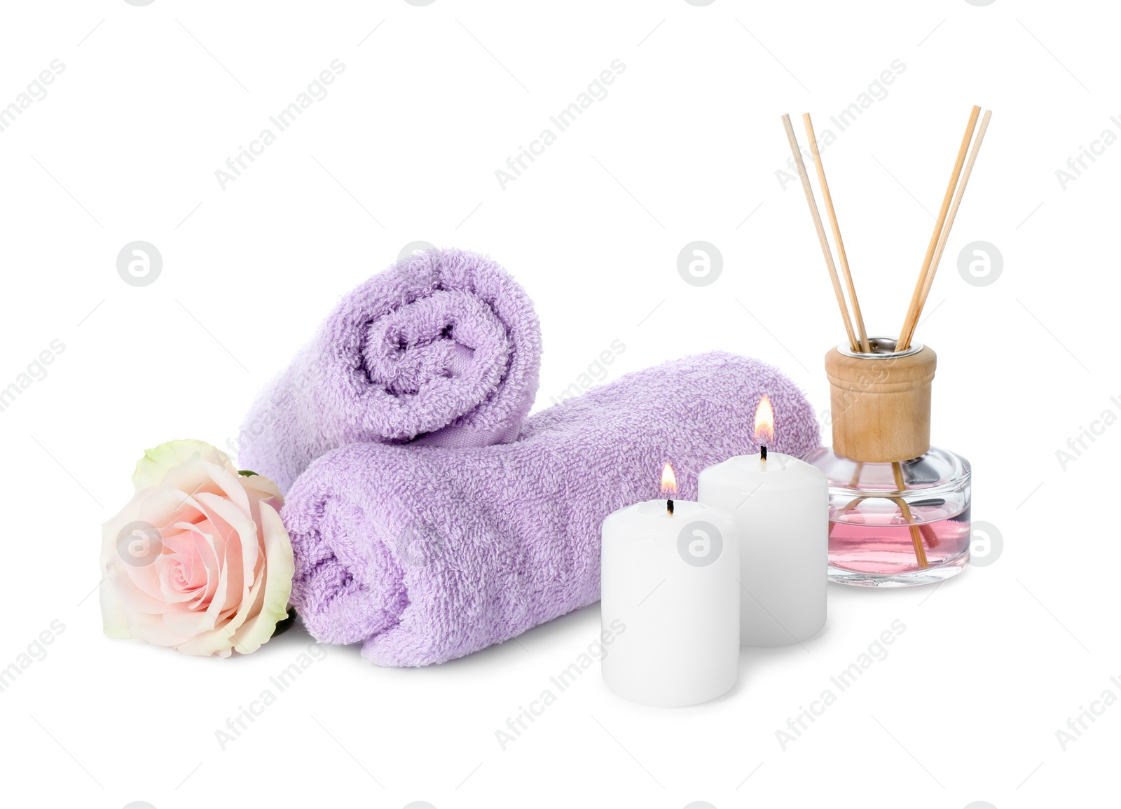 Photo of Spa composition. Towels, burning candles, reed air freshener and rose flower on white background