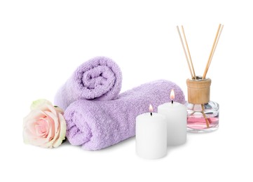 Photo of Spa composition. Towels, burning candles, reed air freshener and rose flower on white background