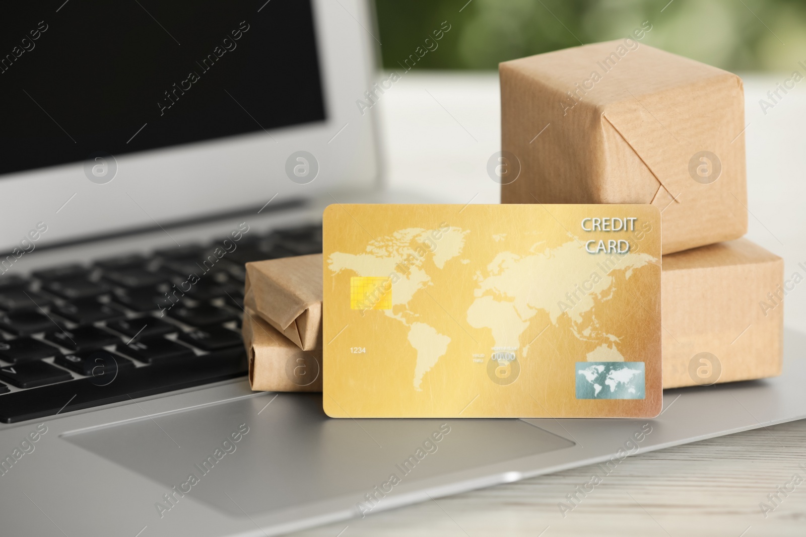 Photo of Online payment concept. Bank card and small boxes with laptop on white table, closeup