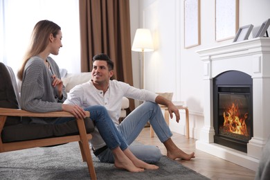 Photo of Happy couple resting near fireplace at home