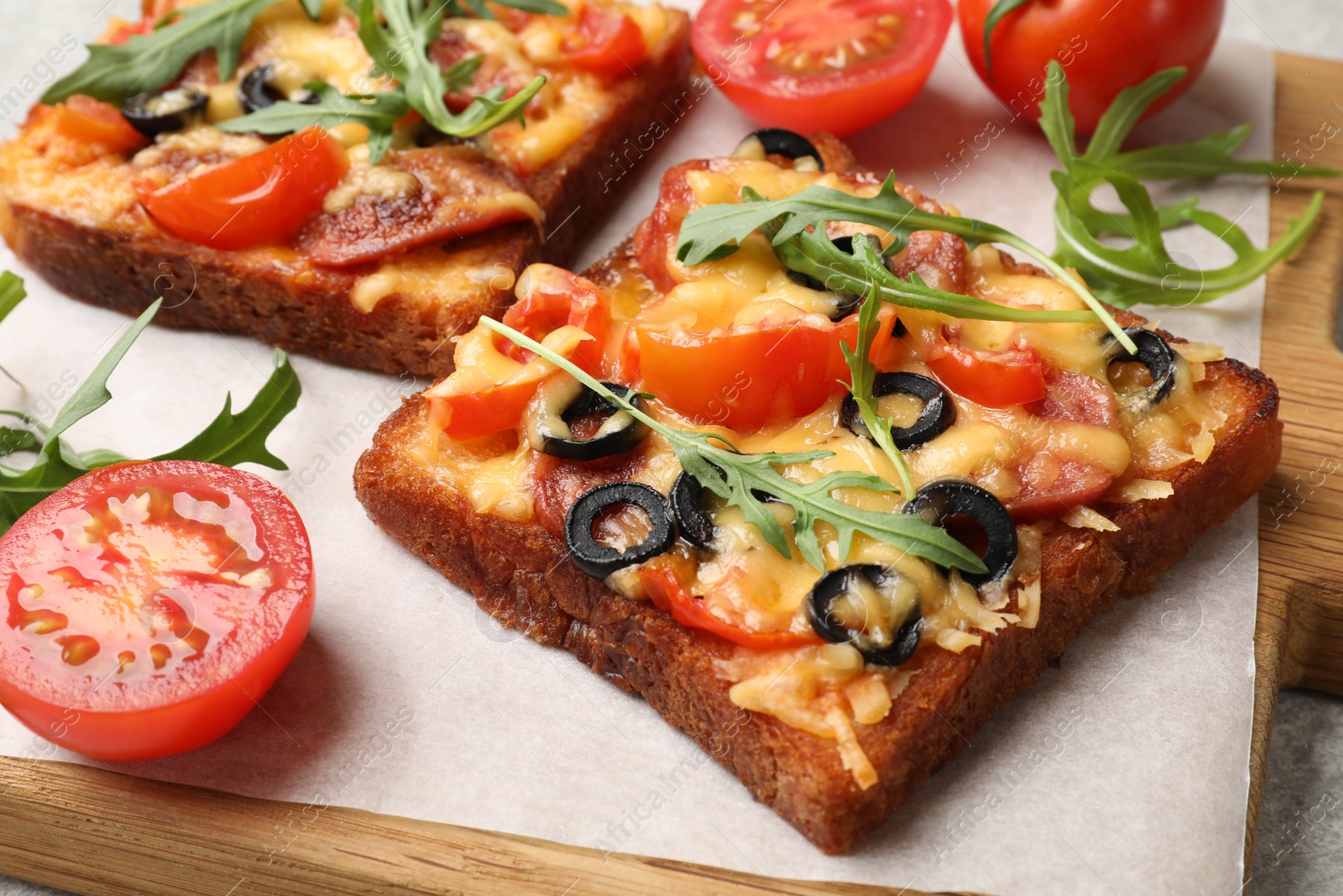 Photo of Tasty pizza toasts, fresh tomatoes and parsley on grey table, closeup