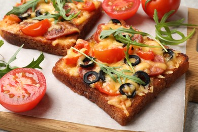 Tasty pizza toasts, fresh tomatoes and parsley on grey table, closeup