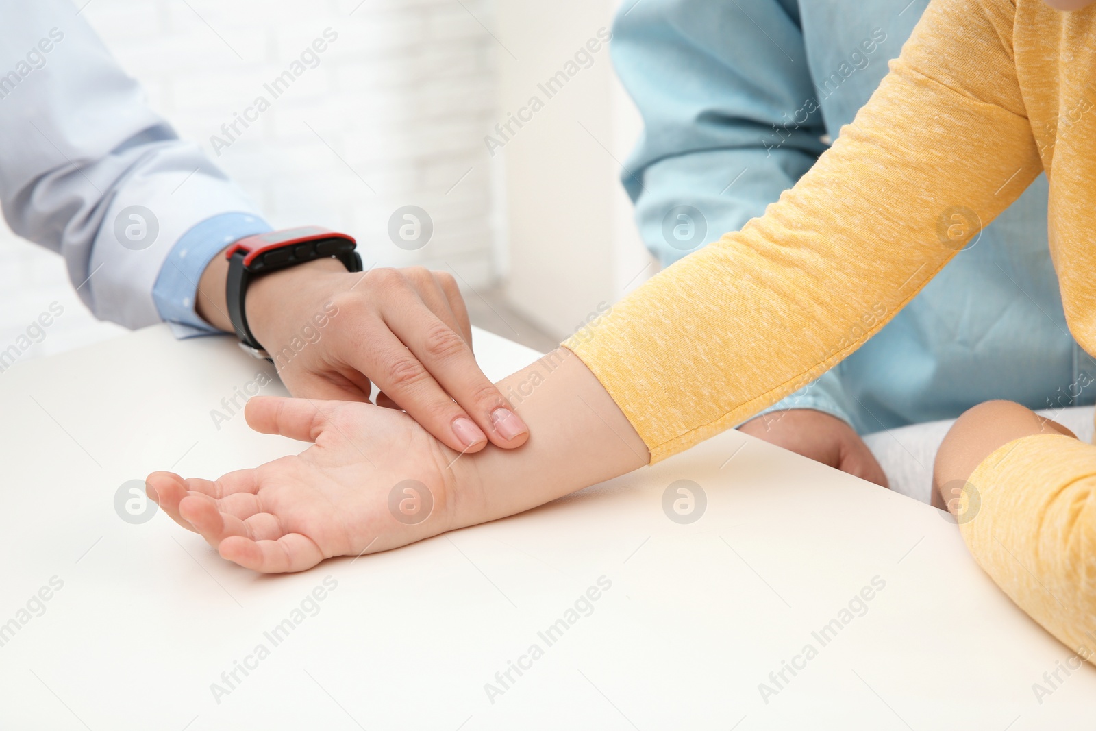 Photo of Doctor checking little girl's pulse with fingers in hospital, closeup