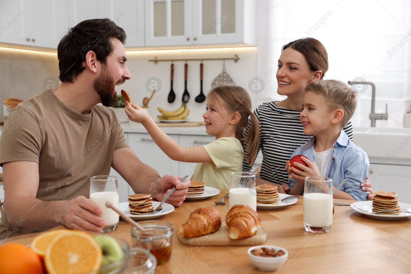 Photo of Happy family having fun during breakfast at table in kitchen