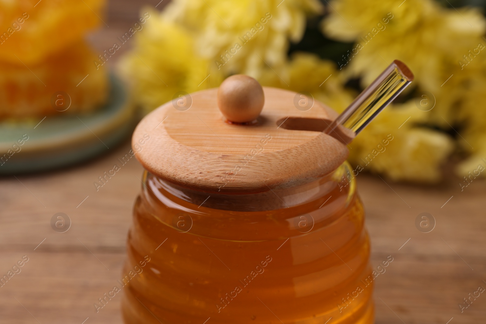 Photo of Sweet golden honey in jar on table, closeup