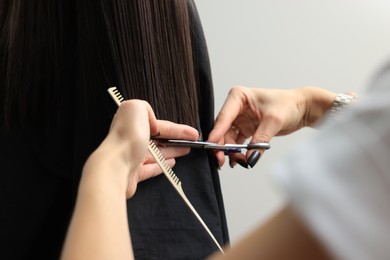 Photo of Professional hairdresser cutting woman's hair, closeup view