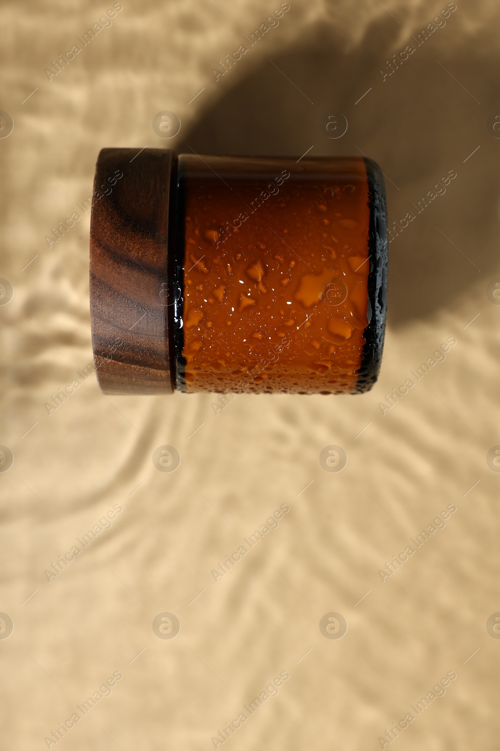Photo of Jar of cosmetic product in water on beige background, top view. Space for text
