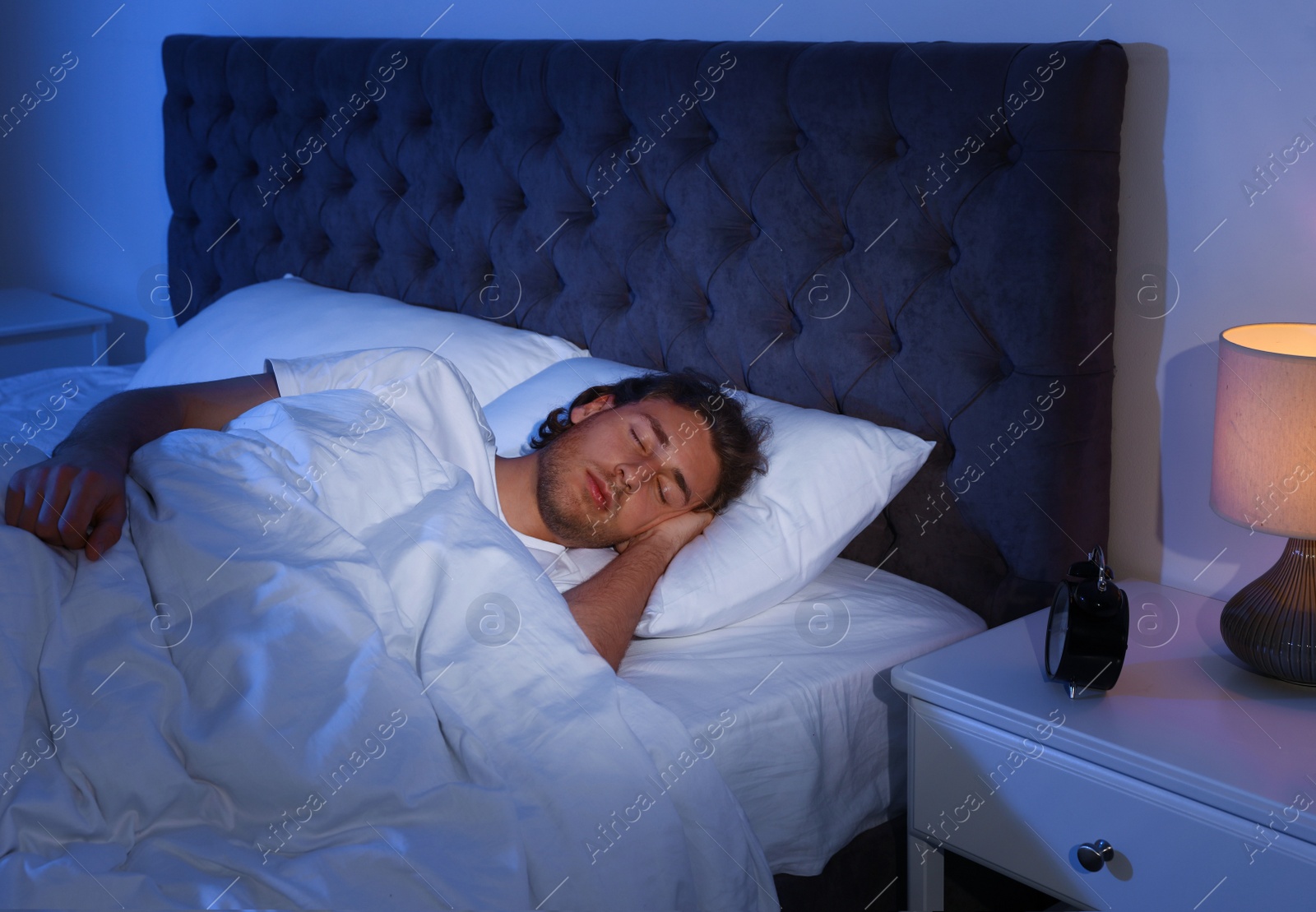 Photo of Handsome young man sleeping on pillow at night. Bedtime