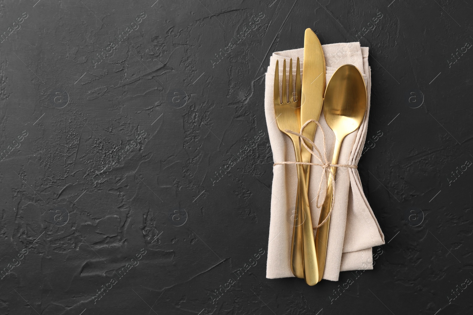 Photo of Set of stylish cutlery and napkin on black table, top view. Space for text